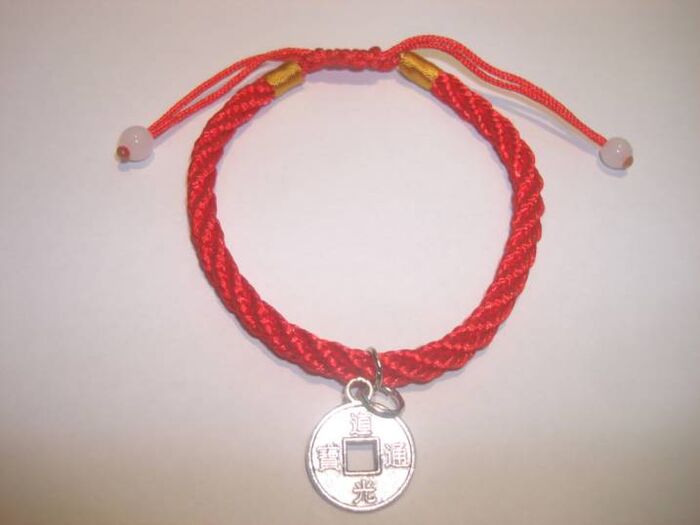 Red thread bracelet with rare coins to attract good luck